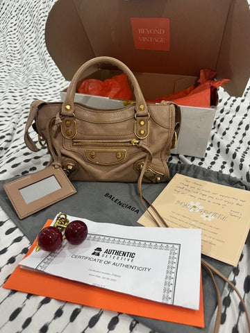 Photo showing a handbag, letter, bag charm, and authenticity certificate being unboxed by the customer.