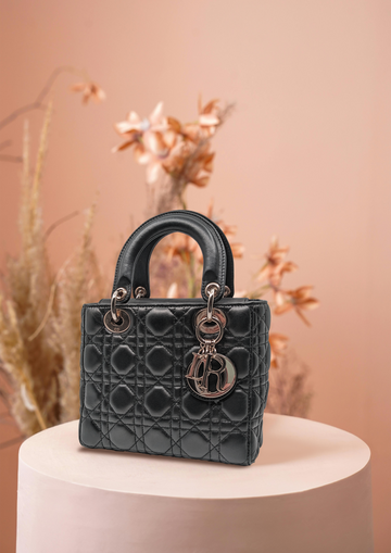 Image displaying an iconic Dior Lady bag in black colour with flowers in light-pink background.